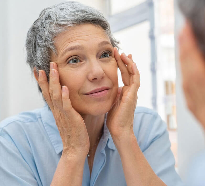 senior woman checking her face skin and looking for blemishes